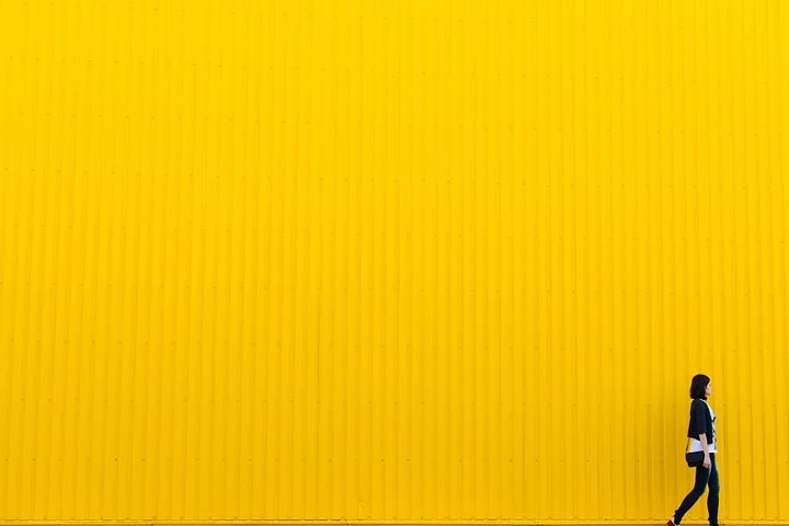 Women Walking through yellow wall