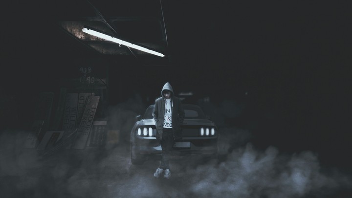 cool guy stands by car in hoody