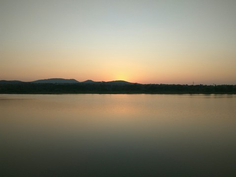 Sunset over a hill by a lake