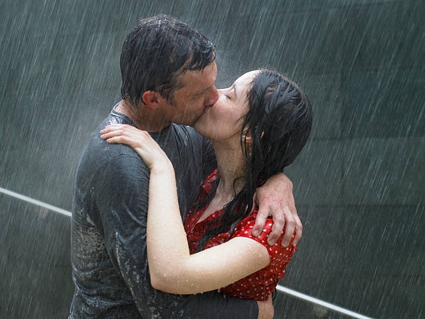Couple kissing in rain, side view, close-up - stock photo