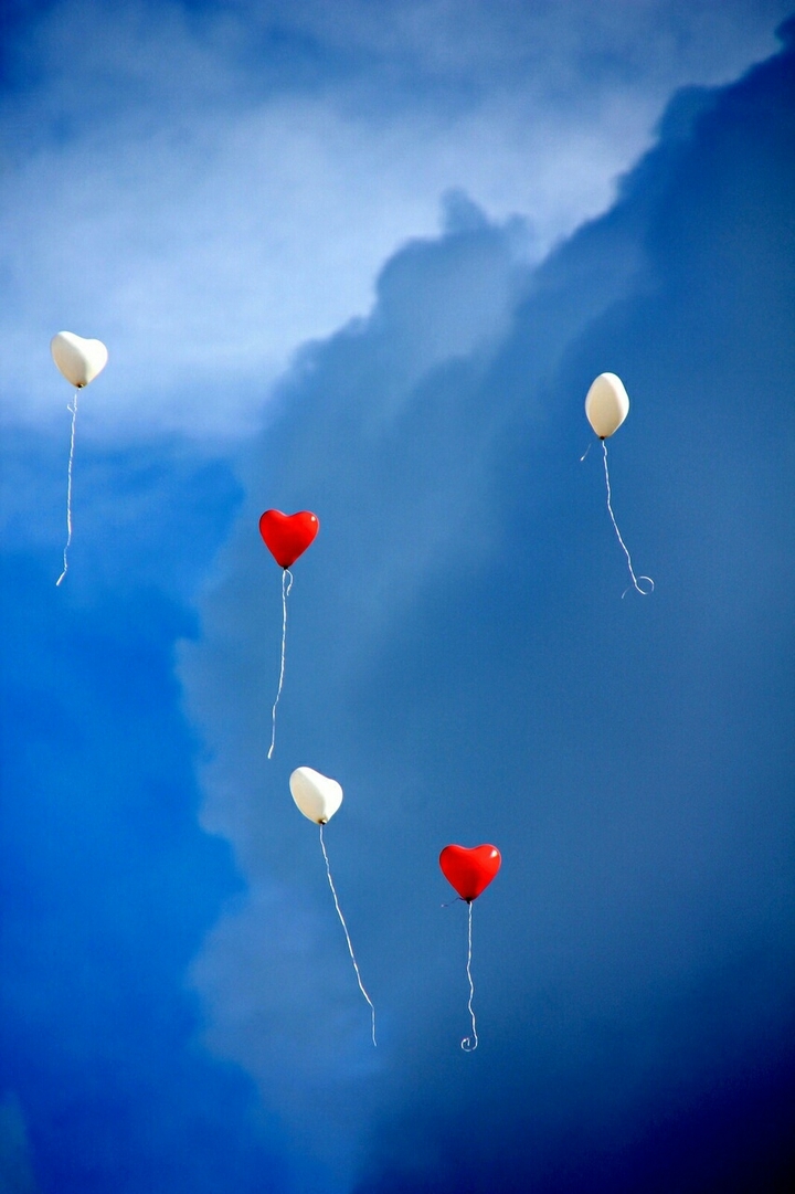 Ballon en coeur blanc et rouge dans un ciel bleu