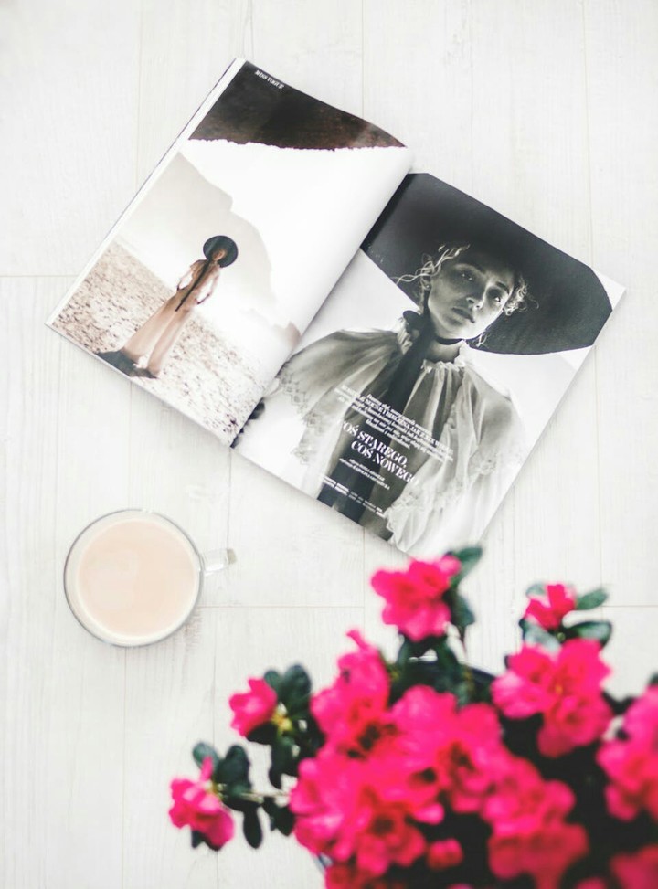A Magazine and a Cup of White Coffee with a Pink Flower