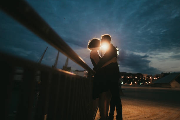 Caucasian couple kissing near railing at night - stock photo