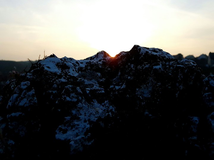 sun goes down behind the rock
