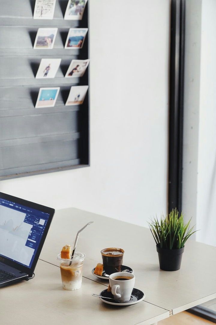 A Two Cup of Coffee and a Laptop with a Green Plant