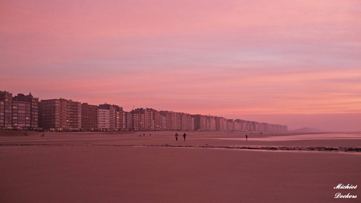 An endless line of buildings with the sky glowing red