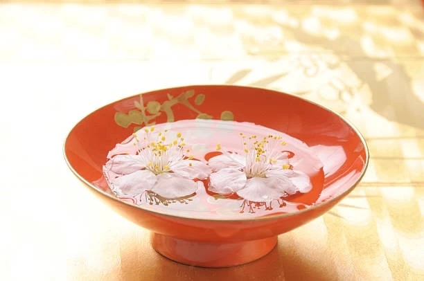 blossoms floating in lacquer sake saucer
