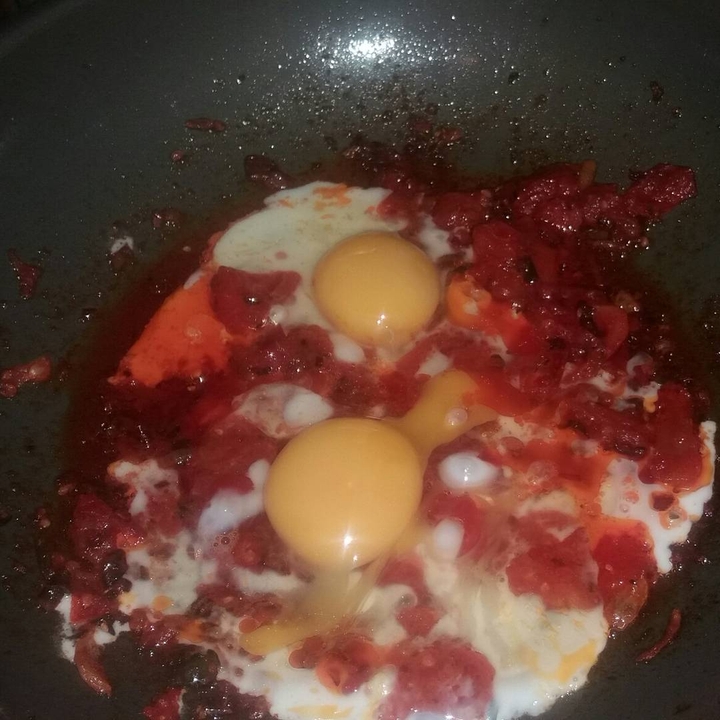 Half fried egg with the base of tomato sauce
