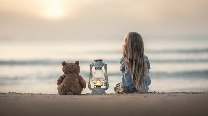 Little Girl Sitting at the Beach with her Teddy Friend
