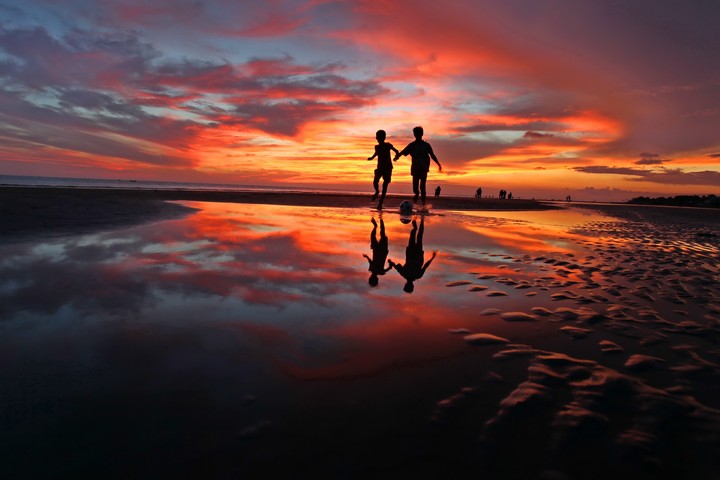 Playing football in beach sunset